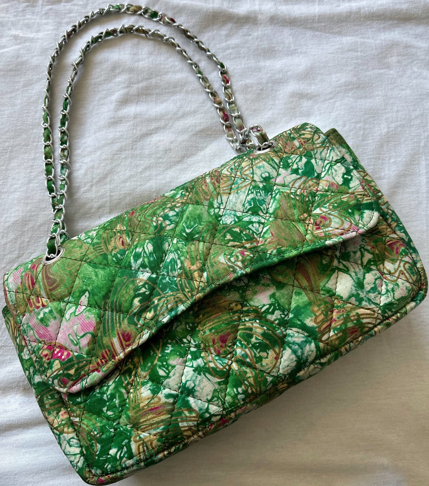 Sac bandoulière matelassé en tissu imprimé africain, motifs verts et roses avec bandoulière en chaîne, élégant et original.