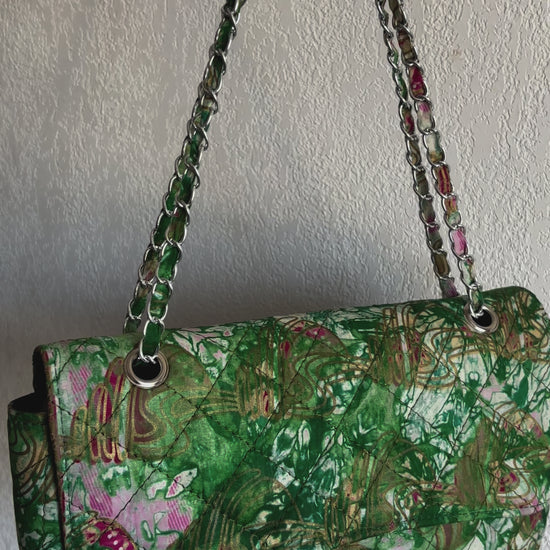 Grand sac bandoulière matelassé en tissu africain imprimé, motifs vibrants en vert, doré et rose, avec bandoulière en chaîne.