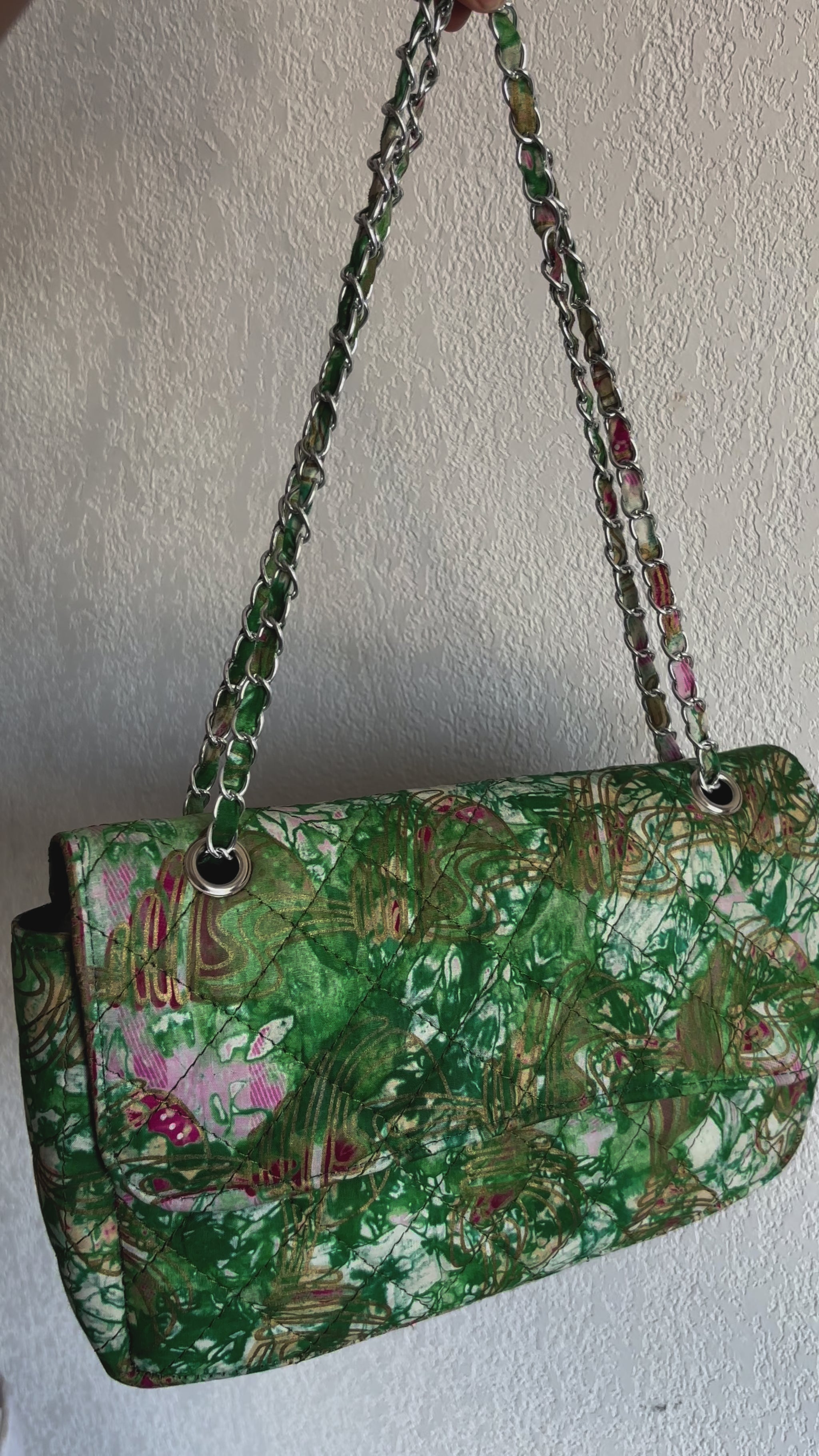 Grand sac bandoulière matelassé en tissu africain imprimé, motifs vibrants en vert, doré et rose, avec bandoulière en chaîne.